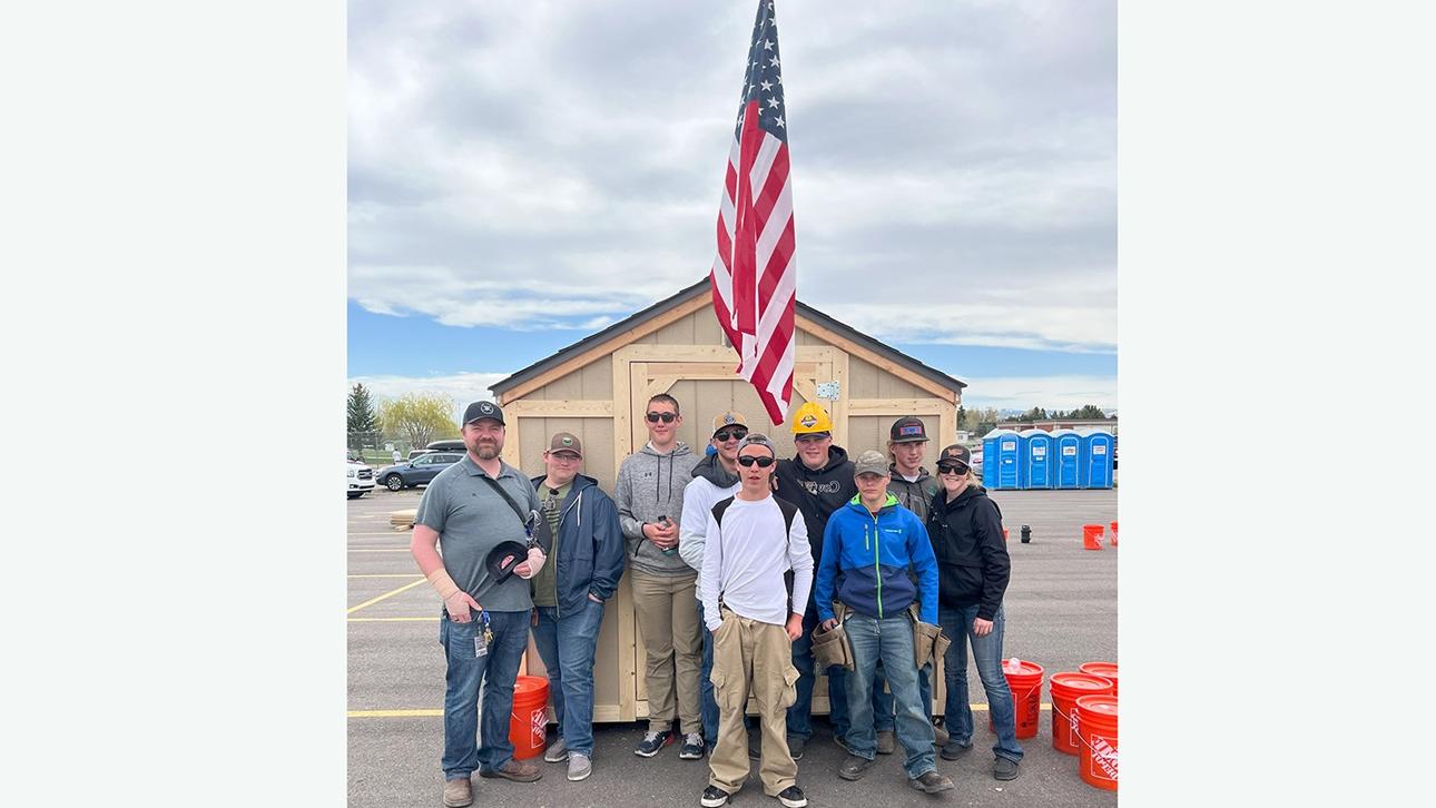 students standing in front of shed with American flag